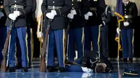 Seorang prajurit Angkatan Darat Honor Guard Amerika tergeletak di lantai karena pingsan saat upacara penghormatan untuk perpisahan Presiden Barack Obama di Arlington, Virginia (1/4). (AFP/Jim Watson)