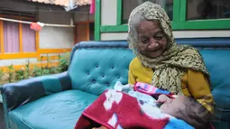 Nenek Anami terlihat menggendong seorang bayi di depan rumahnya di Purwakarta, Jabar, Minggu (17/5). Nenek yang diduga berusia 140 tahun ini akan mengikuti sayembara orang tertua di dunia dengan hadiah sekitar Rp13 miliar. (Liputan6.com/Herman Zakharia)