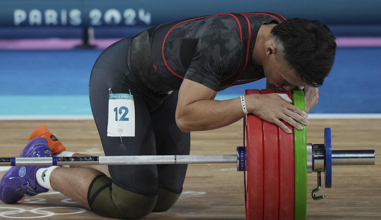 Selebrasi atlet angkat besi Indonesia, Rizki Juniansyah setelah berhasil mengangkat beban seberat 199 kg pada angkatan clean and jerk sekaligus memastikan merebut medali emas saat berlomba pada kelas 73 kg putra cabor angkat besi Olimpiade Paris 2024 di Paris Expo Porte de Versailles, Paris, Kamis (8/8/2024). (AP Photo/Kin Cheung)