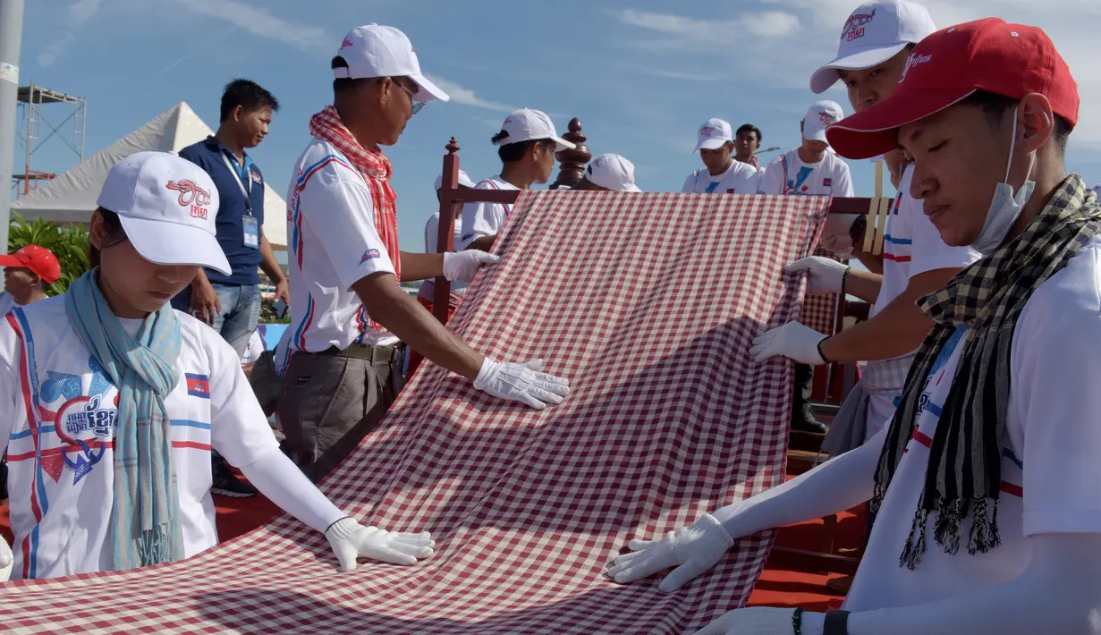 Warga Kamboja membentangkan syal krama sepanjang 1.149,8 meter untuk memecahkan rekor Guinness di Phnom Penh, Minggu (1/7). Syal krama di Kamboja masuk dalam buku Guinness World Records sebagai syal tenun terpanjang di dunia. (AFP/TANG CHHIN Sothy)