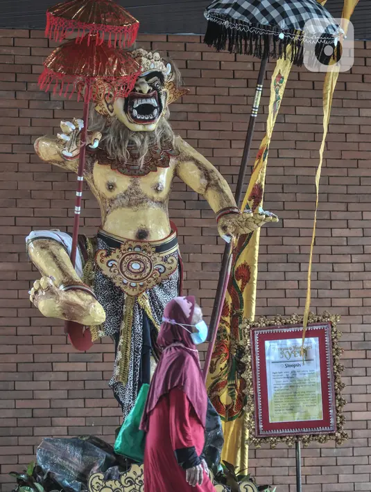 Penumpang Commuter Line atau KRL melintasi patung Ogoh-Ogoh yang dipajang di Stasiun Tebet, Jakarta Selatan, Selasa (1/3/2022). Patung Ogoh-Ogoh tersebut dipajang dalam rangka menyambut Hari Raya Nyepi Tahun Baru Saka 1944 yang jatuh pada 3 Maret mendatang. (merdeka.com/Iqbal S. Nugroho)
