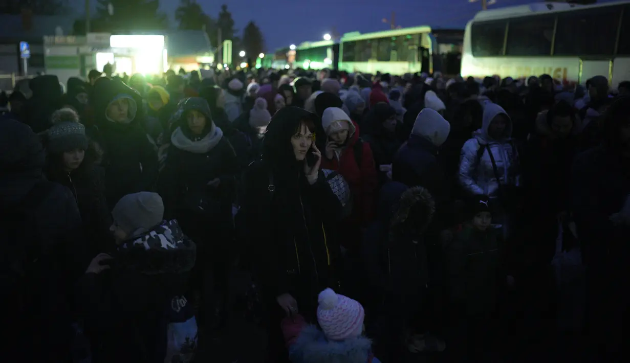 Seorang wanita berbicara di telepon saat dia bergabung dengan para pengungsi yang melarikan diri dari perang di Ukraina membentuk garis mendekati perbatasan dengan Polandia di Shehyni, Ukraina, Minggu (6/3/2022). (AP Photo/Daniel Cole)