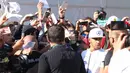Lewis Hamilton dengan kawalan ketat pihak keamanan F1 melayani permintaan tanda tangan dari ratusan fans yang menanti di gerbang masuk arena Sirkuit Monza. (Bola.com/Reza Khomaini)