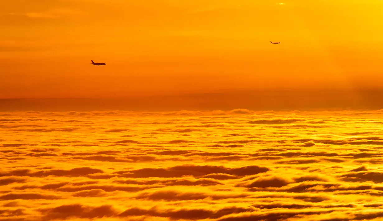 Dua pesawat terbang di atas awan saat matahari terbit sebelum mendarat ke bandara di Frankfurt, Jerman, (28/12). (AP Photo / Michael Probst)