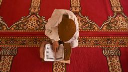 Seorang anak yatim Muslim mengenakan masker bertadarus sambil menjaga jarak sosial di dalam pusat panti asuhan selama bulan suci Ramadan di Srinagar (11/5/2020). (AFP/Tauseff Mustafa)