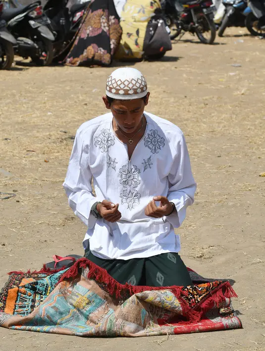 Seorang pria berdoa saat salat Jumat di sebuah ladang di dekat tempat penampungan sementara setelah gempa di Pemenang, Lombok (10/8). Korban tewas akibat gempa dahsyat 6,9 SR di pulau Lombok melonjak di atas 300 orang. (AFP Photo/Adek Berry)