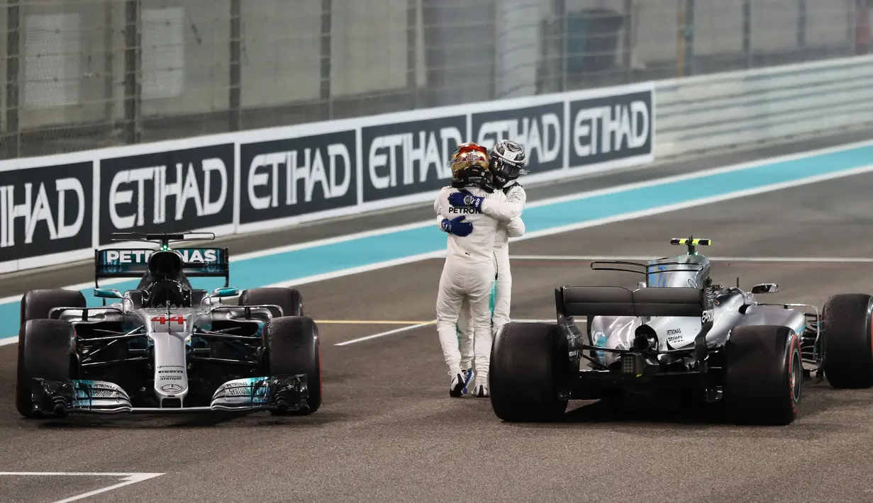 Pebalap Mercedes, Lewis Hamilton (depan) dan rekannya Valtteri Bottas merayakan keberhasilan masuk finis pada balapan F1 Abu Dhabi di Yas Marina circuit , (26/11/2017). Bottas finis pertama. (AFP/Karim Sahib)