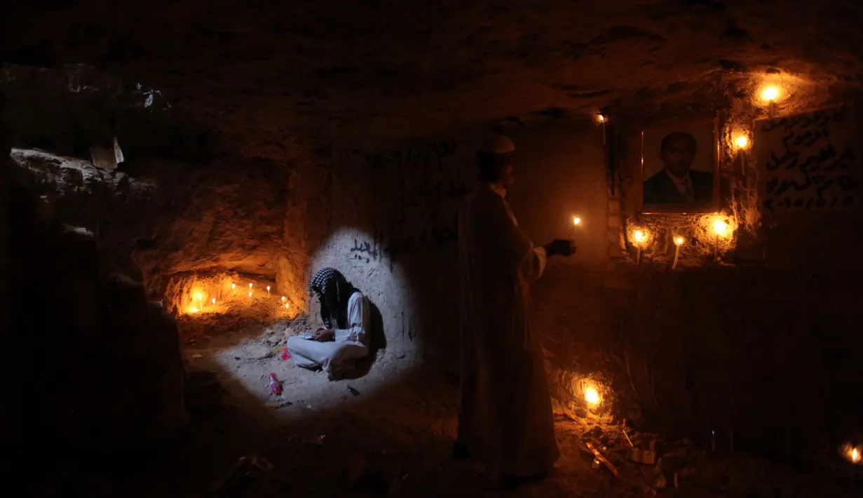 Seorang pria membaca ayat suci Al-Quran di makam kerabatnya di pemakaman Wadi al-Salam, di Najaf, selatan Baghdad, Irak, 28 Juli 2016. Pemakaman tersebut sudah ada sejak 1.400 tahun lalu. (REUTERS/Alaa Al-Marjani)