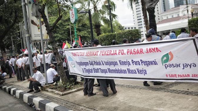 Massa dari SP PD Pasar Jaya membentangkan spanduk dalam unjuk rasa di Balai Kota DKI Jakarta, Rabu (31/1). Mereka menuntut untuk menghentikan rekrutmen tenaga profesional yang melanggar peraturan Pasar Jaya SK 65 Tahun 2016. (Liputan6.com/Faizal Fanani)