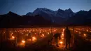 Petani menyalakan api dengan wadah tong di kebun anggur di Flaesch, Swiss (22/3). Ratusan lilin anti-embun per hektar dinyalakan untuk melindungi buah dari dingin. (Gian Ehrenzeller / Keystone via AP)