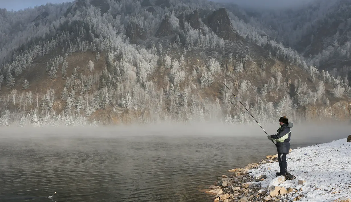 Seorang pria memancing dipinggir sungai Yenisei ditengah kabut dingin di Taiga luar kota Siberia Krasnoyarsk, Rusia, Selasa (17/11/2015). Suhu udara minus hingga 20 derajat Celsius. (REUTERS/Ilya Naymushin)