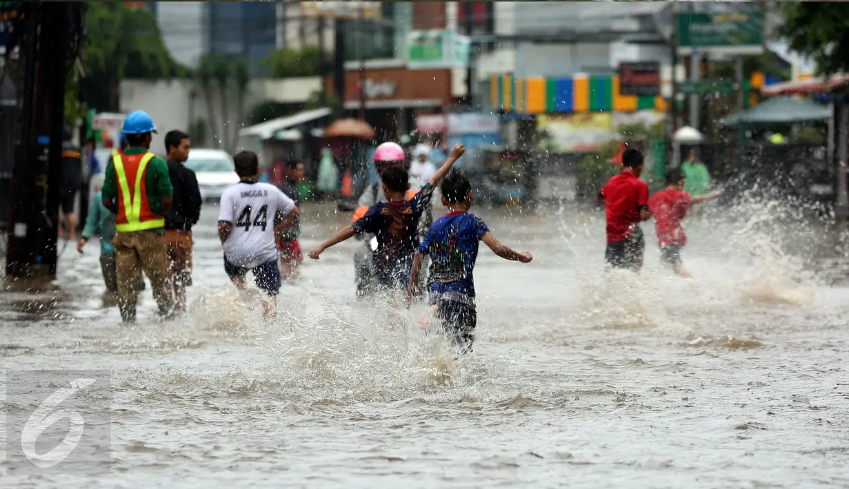 Sejumlah anak berlarian sambil bermain banjir yang merendam kawasan Benhil RT 03 RW 05, Jakarta Pusat, Selasa (21/1). Hujan deras yang mengguyur sejak Selasa dinihari mengakibatkan kawasan tersebut mengalami banjir. (Liputan6.com/Johan Tallo)