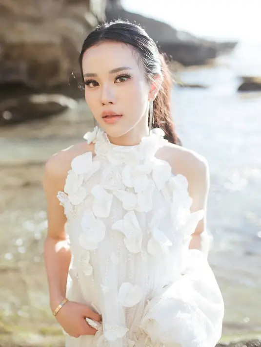 Gaun tersebut memiliki ekor panjang yang mengalir di atas pasir pantai, menciptakan ilusi ethereal yang membuatnya tampak seperti sosok anggun dari negeri dongeng. [@jessicajane].