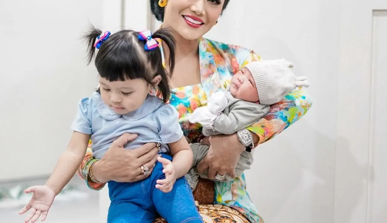 Potret lainnya memperlihatkan Krisdayanti dalam balutan kebaya dan kain batik menggendong kedua cucunya dari Aurel dan Atta. Ia tampil elegan degnan atasan kebaya kutubaru berwarna cerah dipadukan dengan rok batik. [Foto: Instagram/story.of.amoralemos]