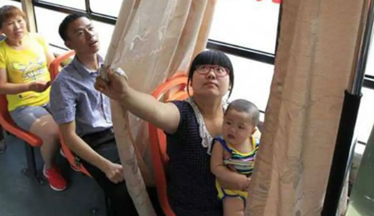 Seorang Ibu saat ingin menutup tirai untuk menyusui anaknya di dalam sebuah bus, kota Pingxiang, Provinsi Jiangxi, Cina. Beberapa kota didaerah Cina sudah menerapkan kursi khusus untuk ibu menyusui didalam angkutan umum. (shanghaiist.com)