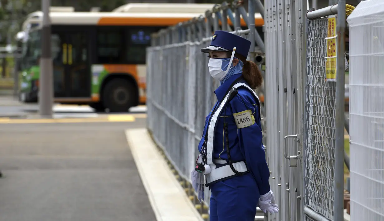 Penjaga mengenakan masker untuk mencegah penyebaran virus corona berdiri di lokasi pembangunan desa atlet yang akan digunakan selama Olimpiade dan Paralimpiade Tokyo 2020 di Tokyo (31/5/2021). Jepang mengkonfirmasi lebih dari 260 kasus virus corona baru pada hari Senin. (AP Photo/Eugene Hoshiko)