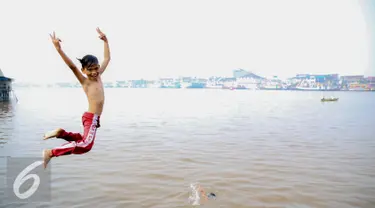 Seorang anak melompat untuk berenang di Sungai Kapuas, Pontianak, Kalimantan Barat, Sabtu (22/8/2015). Anak-anak yang tinggal sekitar Sungai Kapuas biasa mandi dan berenang di aliran tersebut setiap pagi dan sore hari. (Liputan6.com/Faizal Fanani)