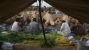 Pedagang duduk dekat unta untuk hewan kurban yang dijual di sebuah pasar hewan di Lahore, Pakistan, Minggu (4/8/2019). Umat Islam di seluruh dunia akan merayakan Hari Raya Idul Adha yang identik dengan tradisi berkurban seperti kambing, domba, onta, sapi dan kerbau. (ARIF ALI / AFP)