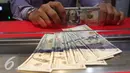 Petugas memperlihatkan uang pecahan US$100 dan rupiah di pusat penukaran uang, Jakarta, Rabu (23/9/2015). Pada perdagangan pagi hingga siang ini, rupiah terus bergerak di kisaran 14.577 per dolar AS hingga 14.658 per dolar. (Liputan6.com/Angga Yuniar)