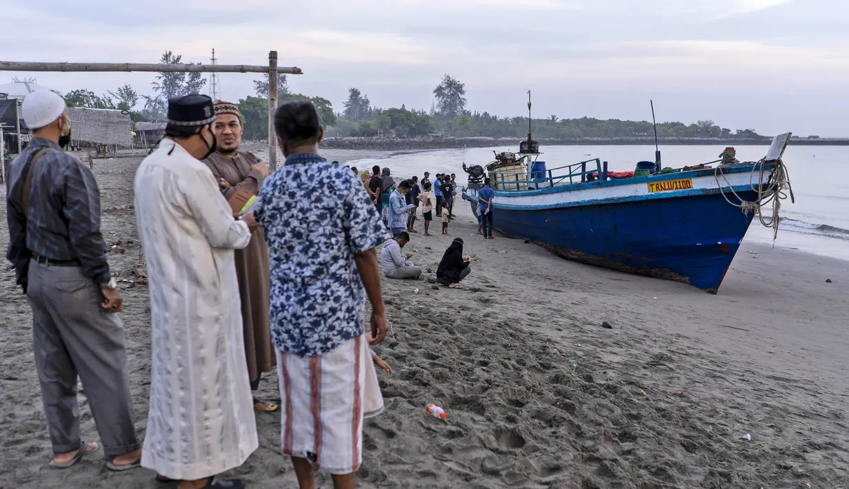 Penduduk setempat memeriksa kapal yang membawa ratusan etnis Rohingya yang mendarat di pantai di Lhokseumawe, provinsi Aceh, Senin (7/9/2020). Hampir 300 Muslim Rohingya ditemukan di sebuah pantai di provinsi Aceh dan dievakuasi oleh militer, polisi dan Relawan. (AP Photo/Zik Maulana)