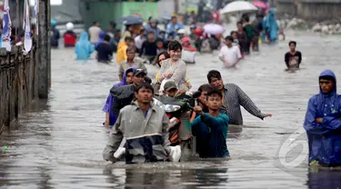 Sejumlah warga terpaksa menggunakan jasa gerobak untuk melintasi banjir yang setinggi dada orang dewasa di Jalan Gunung Sahari, Jakarta, Senin (6/2/2015). (Liputan6.com/Faizal Fanani)