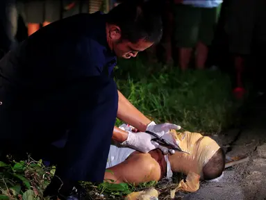 Petugas memotong lilitan lakban wajah seorang jenazah pria di sebuah jalan di kota Pasay, metro Manila, Filipina (17/11). Belakangan, banyak korban yang merupakan pecandu dan bandar di Filipina tewas dalam kondisi mengenaskan. (Reuters/Romeo Ranoco)