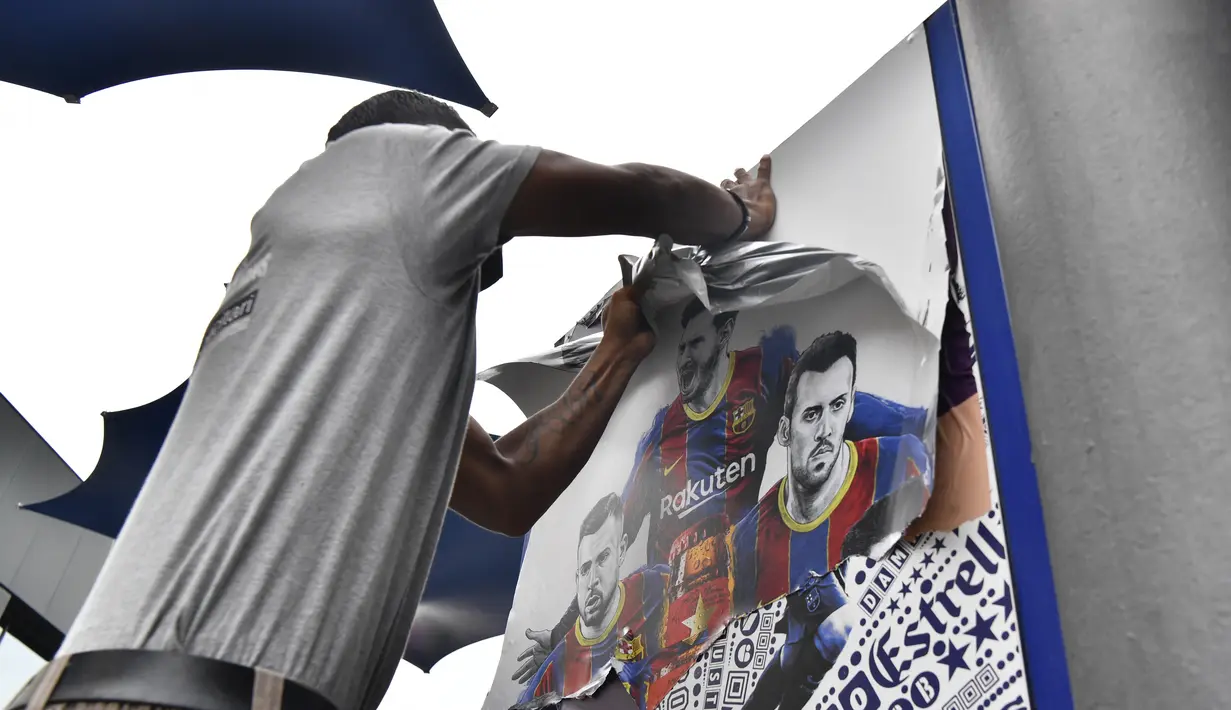 Seorang pekerja melepas poster-poster yang menampilkan pemain depan Barcelona Lionel Messi di stadion Camp Nou di Barcelona (10/8/2021). Prancis menunggu dengan tidak sabar Lionel Messi dengan para pendukung berkumpul di luar lapangan Paris Saint-Germain. (AFP/ Pau Barrena)