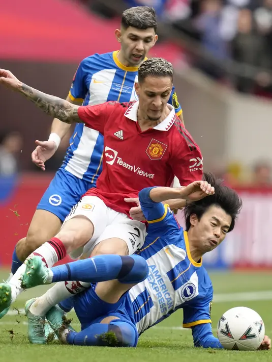 Pemain Manchester United, Antony (tengah) berebut bola dengan pemain Brighton, Kaoru Mitoma (kanan) pada laga semifinal Piala FA 2022/2023 di Stadion Wembley, London, Minggu (23/04/2023). Laga dimenangkan oleh MU dengan skor 7-6 melalui babak adu penalti. (AP Photo/Kirsty Wigglesworth)