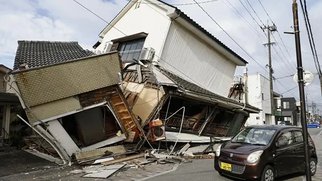 Sebuah kendaraan melintas di dekat rumah-rumah yang runtuh di Yatsushiro, Prefektur Kumamoto, Rabu (29/7/2026), pasca gempa Jepang.