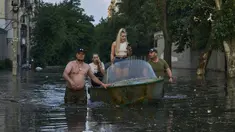 Petugas penyelamat berusaha menarik perahu yang membawa penduduk yang dievakuasi dari lingkungan banjir di Kherson, Ukraina, Selasa (6/6/2023). Tembok bendungan besar di bagian selatan Ukraina telah runtuh, memicu banjir, membahayakan pembangkit listrik tenaga nuklir terbesar di Eropa dan mengancam persediaan air minum. (AP Photo/Libkos)