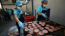 Relawan menggoreng daging bologna untuk pengungsi Venezuela di tempat penampungan Divina Providencia, La Parada, Cucuta, Kolombia, Senin (18/2). Sebagian besar makanan disiapkan untuk imigran Venezuela. (AP Photo/Fernando Vergara)