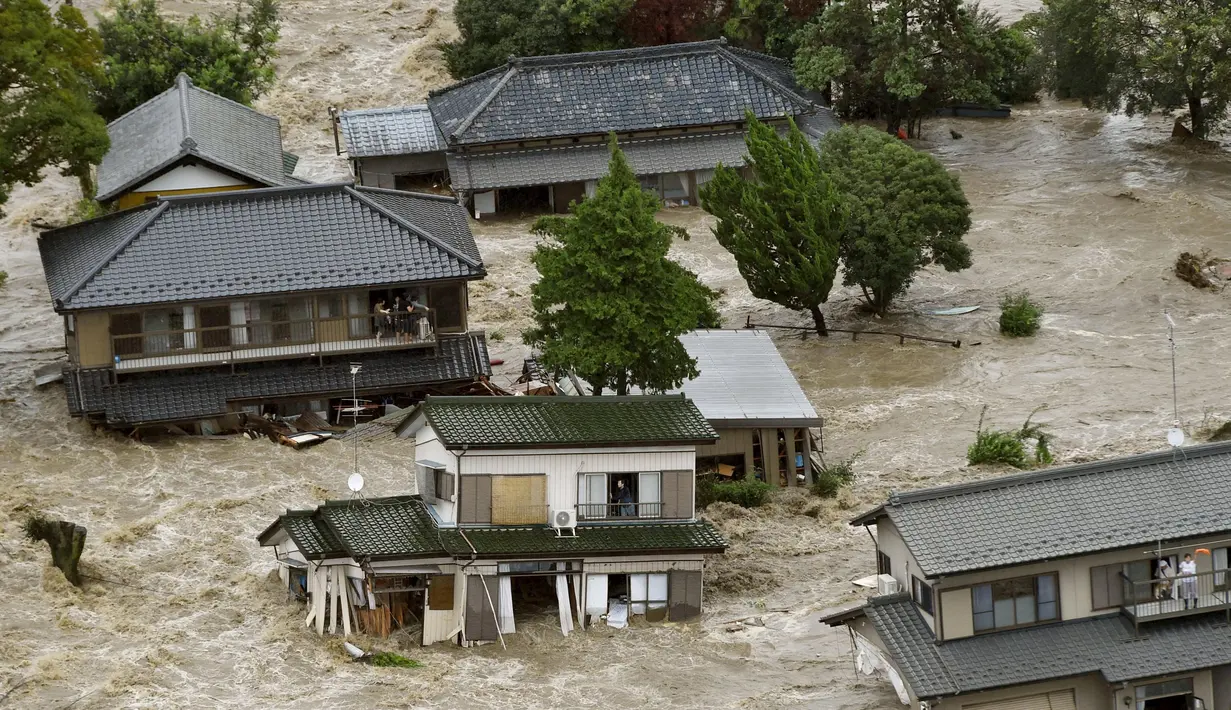 Warga yang terjebak luapan banjir dari Sungai Kinugawa di Joso, prefektur Ibaraki, menunggu dievakusi tim penyelamat, Jepang, Kamis (10/9). Satu orang hilang dan lebih dari 90 ribu warga diperintahkan untuk mengungsi. (REUTERS/Kyodo)