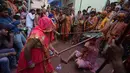 Pria saat dipukuli para wanita dengan tongkat (lathi) selama perayaan Lathmar Holi di Barsana di Mathura, India, (24/2). Lathmar Holi adalah perayaan lokal festival Hindu Holi, biasanya beberapa hari sebelum festival Holi. (AFP Photo/Dominique Faget)