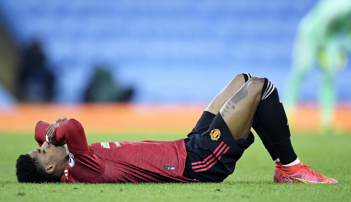 Striker Manchester United, Marcus Rashford berbaring di lapangan usai mengalami cedera saat menghadapi Manchester City dalam laga lanjutan Liga Inggris 2020/21 di Etihad Stadium, Minggu (7/3/2021). MU menang 2-0 atas Mancity. (AFP/Peter Powell/Pool)