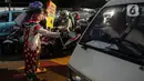 Angggota Komunitas Aku Badut Indonesia (ABI) melakukan aksi kampanye penggunaan di kawasan Cilandak, Jakarta Selatan, Senin (12/7/2021). Selain itu, mereka juga membagi-bagikan masker secara gratis bagi para pengendara motor yang melintas. (Liputan6.com/Johan Tallo)