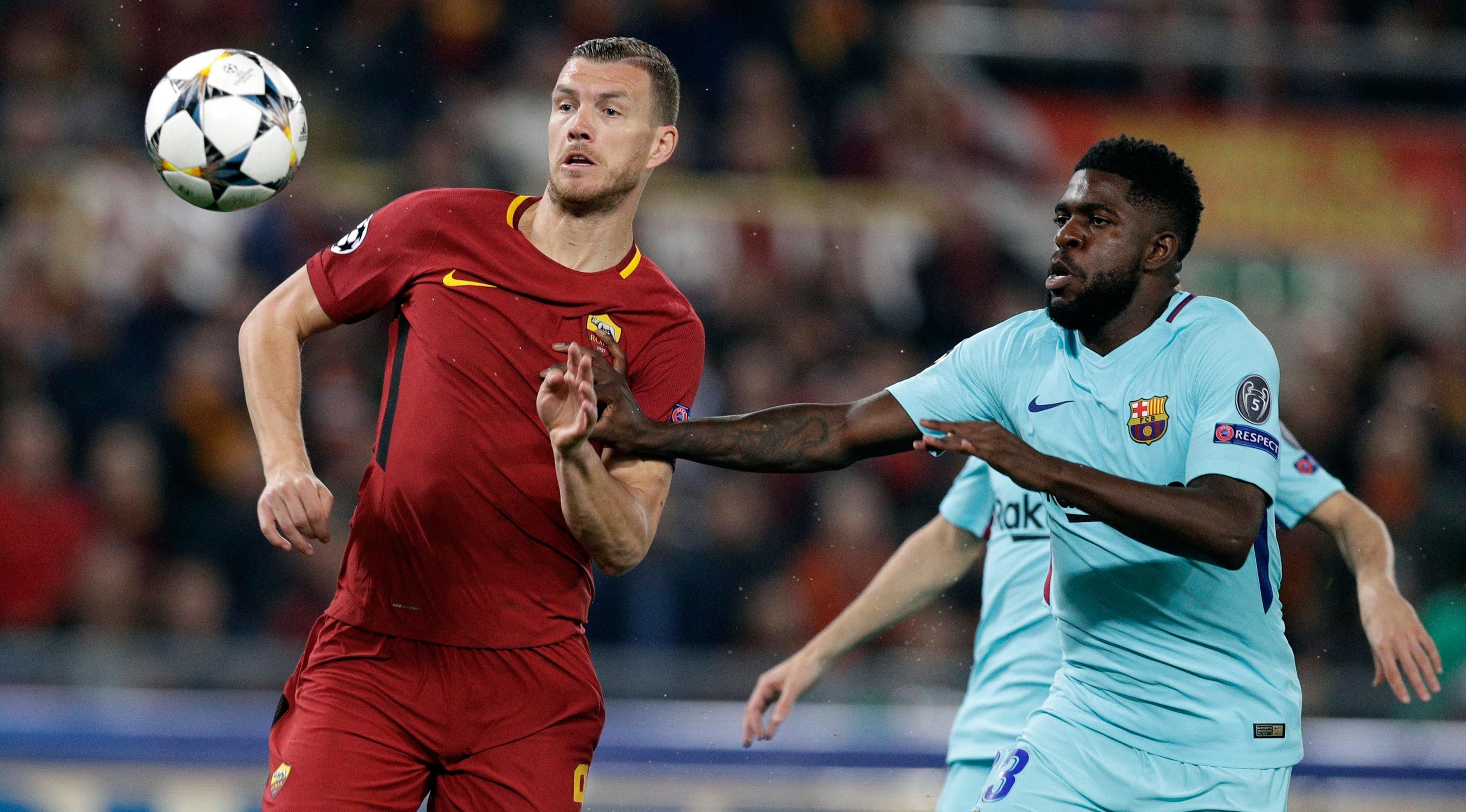 Pemain AS Roma Edin Dzeko berebut bola dengan pemain Barcelona, Samuel Umtiti pada laga leg kedua perempat final Liga Champions di Stadion Olimpico, Selasa (10/4). AS Roma sukses menggilas Barcelona 3-0 untuk merebut tiket semifinal. (AP/Gregorio Borgia)