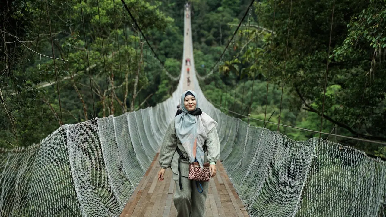 Wanita menyeberangi jembatan Gantung Situ Gunung di Sukabumi (Foto: Pexels)
