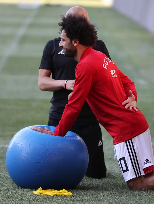 Pemain timnas Mesir Mohamed Salah bersama tim kesehatan melatih bahunya selama sesi pelatihan di stadion Akhmat Arena di Grozny (12/6). Meski masih dibekap cedera bahu, Salah tetap optimis dapat tampil di Piala Dunia 2018 Rusia. (AFP Photo/Karim Jaafar)