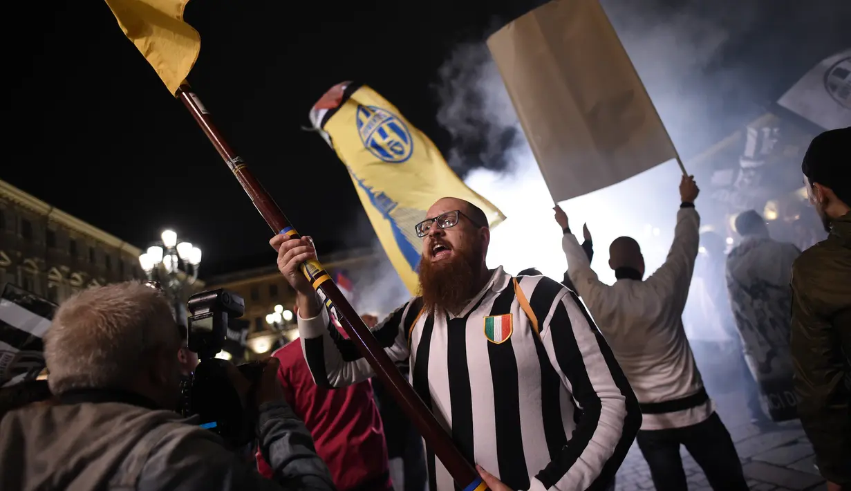 Pendukung Juventus merayakan gelar juara Liga Serie A Italia di Turin (13/5). Juventus bermain imbang 0-0 atas Roma dan memastikan tim asuhan Massimiliano Allegri meraih scudetto. (AFP Photo/Marco Bertorello)