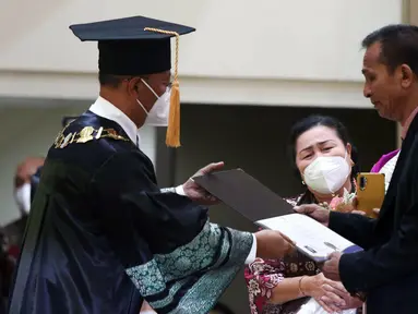 Ayah Brigadir Nofriansyah Yosua Hutabarat atau Brigadir J, Samuel Hutabarat (kanan) menerima ijazah dari Rektor Universitas Terbuka Ojat Darojat saat mewakili anaknya mengikuti prosesi wisuda di Universitas Terbuka, Pamulang, Tangerang Selatan, Banten, Selasa (23/8/2022). Brigadir J tercatat sebagai mahasiswa Program Studi Ilmu Hukum, Fakultas Hukum dan Ilmu Sosial dan Ilmu Politik di Unit Program Belajar Jarak Jauh Universitas Terbuka Jambi. (Liputan6.com/Herman Zakharia)