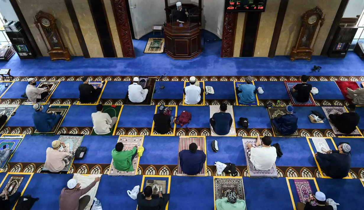 Umat muslim menjaga jarak saat salat Jumat usai pencabutan pembatasan Covid-19 di Masjid Al-Istighfar, Singapura, Jumat (26/6/2020). Masjid-masjid di Singapura telah diizinkan menggelar salat berjamaah, seiring memasuki pekan kedua dari Tahap Dua pembukaan kembali di negara itu. (Roslan RAHMAN/AFP)