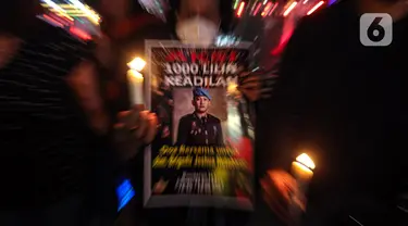 Massa aksi yang tergabung dalam Tim Advokat Penegak Hukum dan Keadilan (Tampak) menunjukkan poster bergambar Brigadir Yosua Hutabarat atau Brigadir J saat aksi 1000 lilin atas kematiannya di Bundaran HI, Jakarta, Jumat (22/7/2022). Aksi tersebut sebagai bentuk keadilan terkait kematian Brigadir J yang diduga akibat penyiksaan. (Liputan6.com/Faizal Fanani)