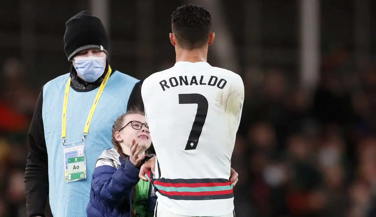 Penyerang Portugal Cristiano Ronaldo memberikan jerseynya untuk fans cilik Irlandia pada akhir laga Grup A Kualifikasi Piala Dunia 2022 Zona Eropa di Stadion Aviva, Jumat (12/11/2021) dinihari WIB. Fans cilik itu nekat menerobos petugas keamanan stadion untuk bertemu Ronaldo. (AP/Peter Morrison)