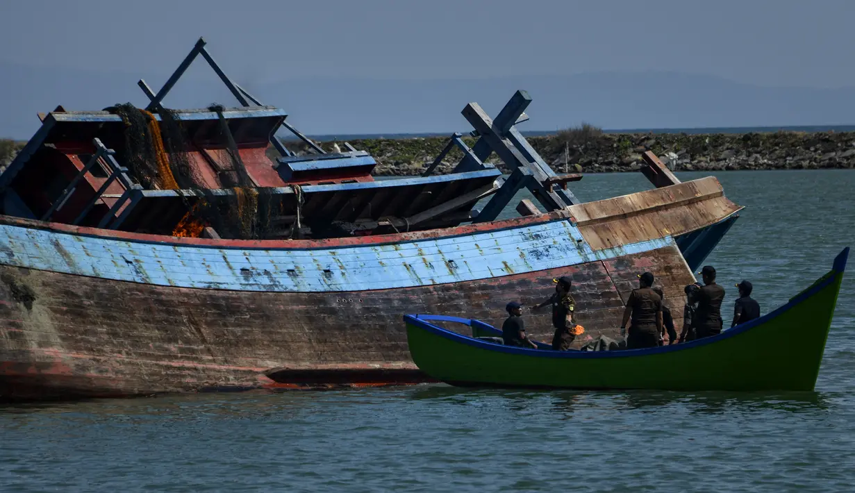 Petugas bersiap menenggelamkan kapal asing ilegal asal Malaysia di perairan Pelabuhan Perikanan Samudera Kutaraja, Banda Aceh (18/3/2021). Dua kapal asing asal Malaysia tersebut diledakkan dan ditenggelamkan setelah diputus bersalah dalam perkara tindak pidana perikanan. (AFP/Chaideer Mahyuddin)