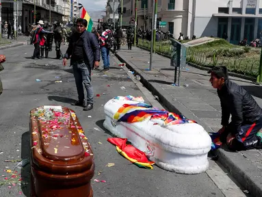 Peti mati berisi jenazah orang yang tewas dalam bentrokan antara pasukan keamanan dengan pendukung mantan Presiden Evo Morales tergeletak di tengah jalan setelah polisi meluncurkan gas air mata pada prosesi pemakaman besar-besaran di El Paz, Bolivia, Kamis (21/11/2019). (AP Photo/Juan Karita)
