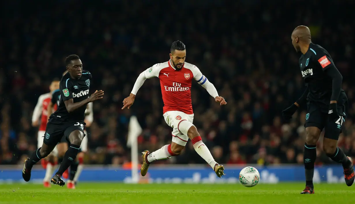 Pemain Arsenal, Theo Walcott mengendalikan bola dikawal pemain West Ham, Domingos Quina dan Andre Ayew dalam lanjutan pertandingan Liga Inggris di Stadion Emirates, Minggu (22/4). Arsenal mampu unggul telak dengan skor 4-1. (AP/Alastair Grant)