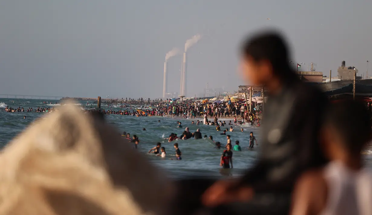 Warga Palestina bermain air di pantai Beit Lahia di Jalur Gaza utara saat para siswa memulai liburan musim panas mereka pada 3 Juni 2022. Sejumlah warga menikmati musim panas dengan berenang dan bermain air di pantai. (MOHAMMED ABED / AFP)