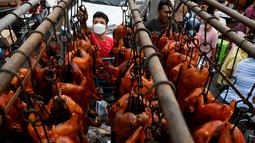 Pekerja menurunkan babi panggang di pasar menjelang Tahun Baru Imlek yang menyambut Tahun Macan di Phnom Penh, Kamboja, Senin (31/1/2022). Menyambut Tahun Baru Imlek, warga Kamboja mempersiapkan daging babi panggang untuk sajian makan. (AFP/Tang Chhin Sothy)