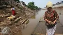 Warga menaiki eretan untuk menyeberangi Kali Ciliwung, Jakarta, Senin (30/11). Tidak adanya fasilitas jembatan menyebabkan warga memilih eretan sebagai sarana penyeberangan sehari-hari, meskipun dengan kondisi seadanya. (Liputan6.com/Immnuel Antonius)