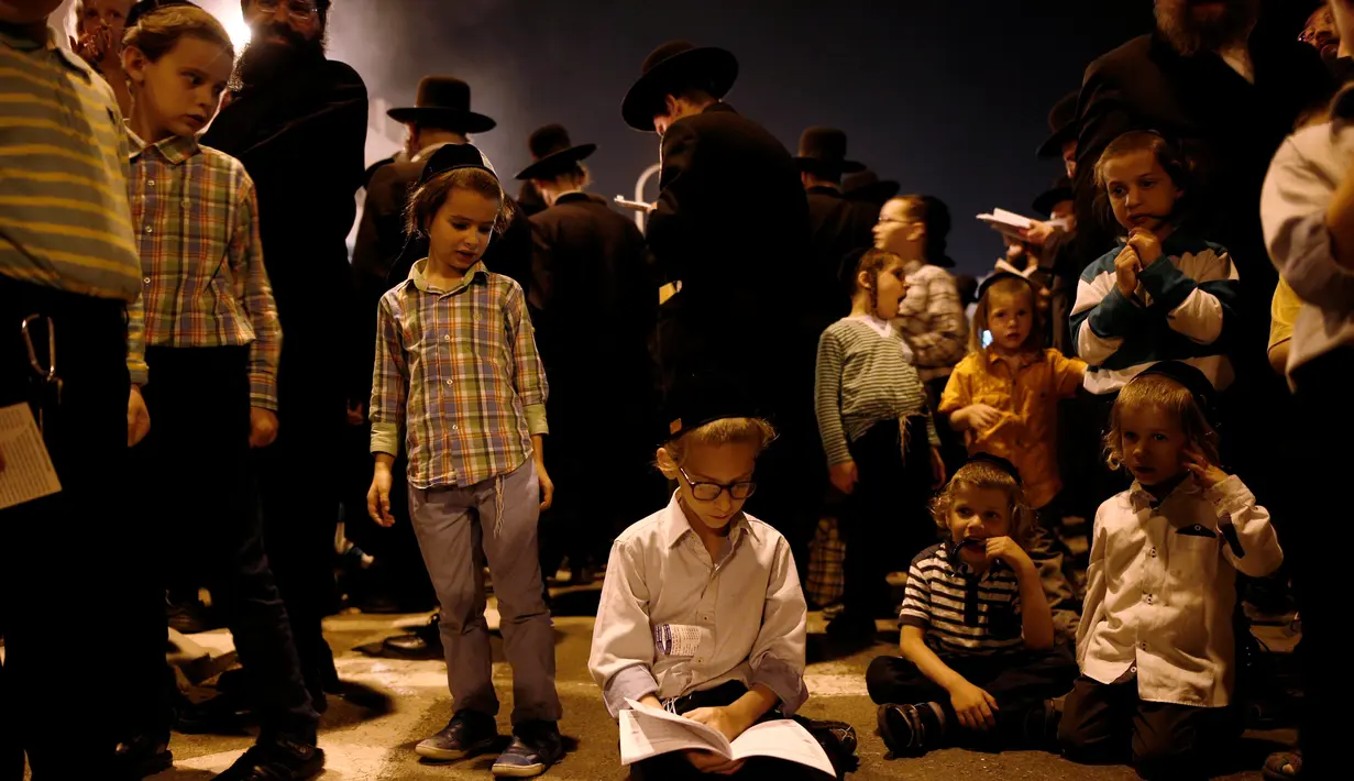 Seorang anak Yahudi Ultra-Ortodoks membaca kitab saat perayaan hari libur Yahudi Lag Ba-Omer di Shearim, Yerusalem, (25/5). Hari libur Yahudi ini terjadi pada hari ke-18 dari bulan Ibrani dari Iyar. (REUTERS/Ronen Zvulun)